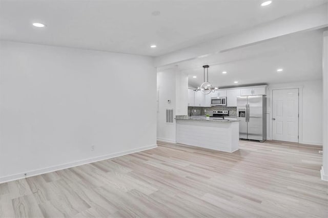 kitchen with light wood-style flooring, stainless steel appliances, white cabinetry, hanging light fixtures, and decorative backsplash