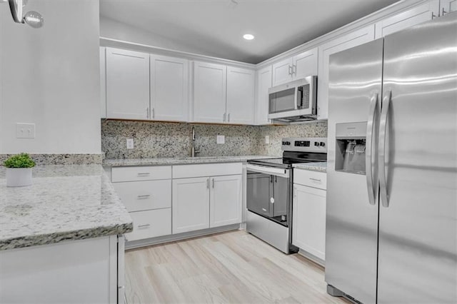 kitchen with tasteful backsplash, white cabinetry, stainless steel appliances, and a sink