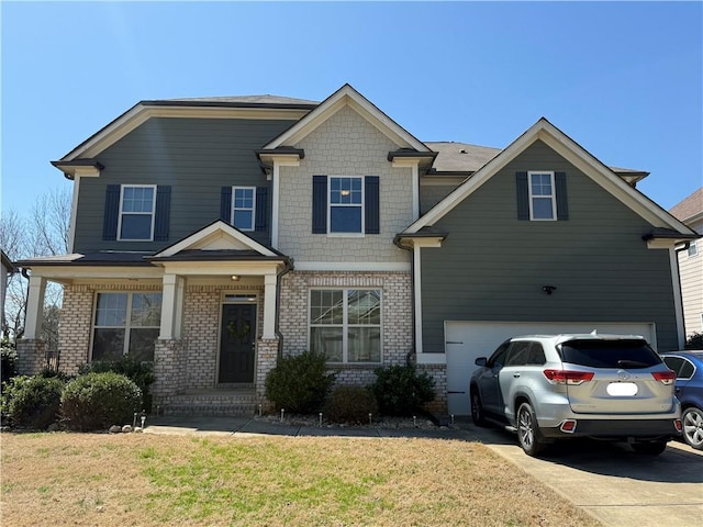 craftsman-style house with brick siding, a front yard, driveway, and a garage