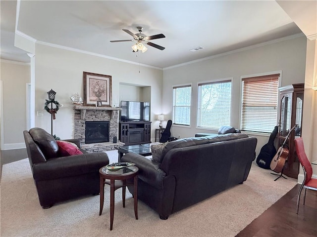 living room with crown molding, carpet flooring, a ceiling fan, a fireplace, and visible vents