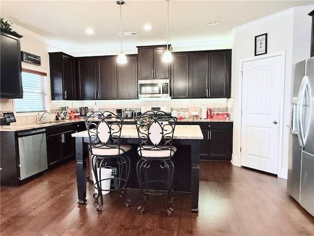 kitchen with ornamental molding, appliances with stainless steel finishes, dark wood-type flooring, and visible vents