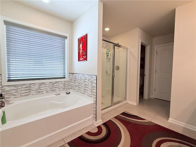 bathroom featuring tile patterned floors, a shower stall, baseboards, and a bath