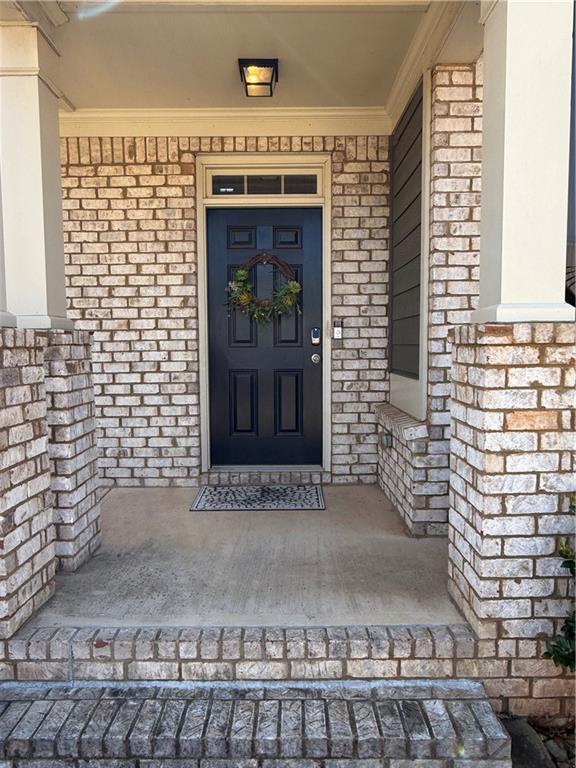 property entrance featuring a porch and brick siding