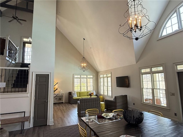 dining area with stairs, ceiling fan with notable chandelier, high vaulted ceiling, baseboards, and wood finished floors