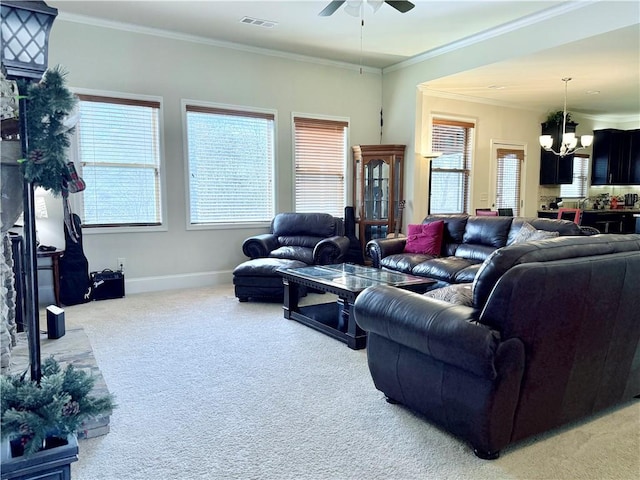 living area with ornamental molding, ceiling fan with notable chandelier, baseboards, visible vents, and light carpet