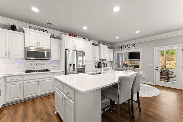2213 Independence Ln, Buford, GA 30519 - kitchen with stainless steel appliances, ornamental molding, an island with sink, a breakfast bar area, and decorative backsplash