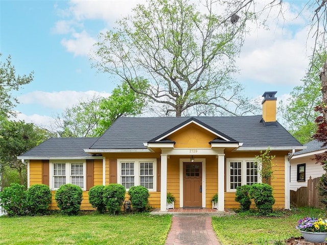 view of front of home featuring a front lawn, fence, and a chimney