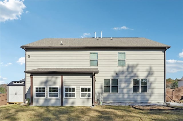 rear view of house featuring a lawn and a storage shed