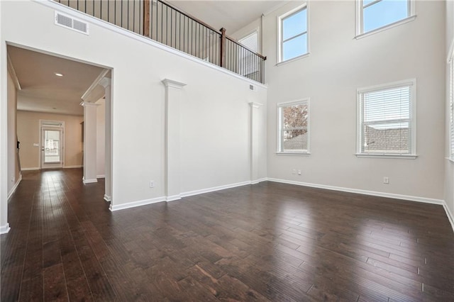 interior space featuring plenty of natural light, a towering ceiling, and dark wood-type flooring