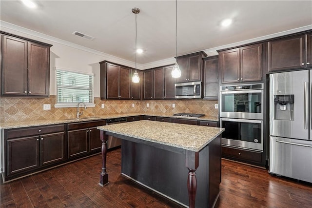 kitchen with ornamental molding, stainless steel appliances, dark wood-type flooring, pendant lighting, and a kitchen island