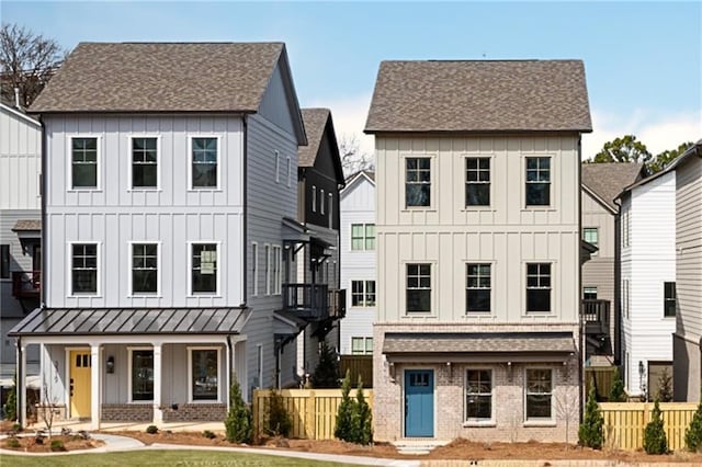 modern farmhouse style home featuring roof with shingles, board and batten siding, covered porch, and brick siding