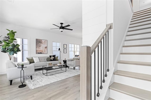 living area with light wood-type flooring, stairway, and a ceiling fan