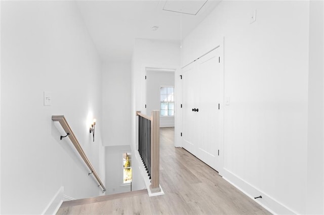 hall featuring light wood-type flooring, attic access, and an upstairs landing