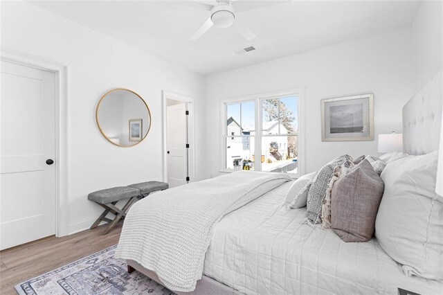 bedroom with wood finished floors, ceiling fan, and visible vents