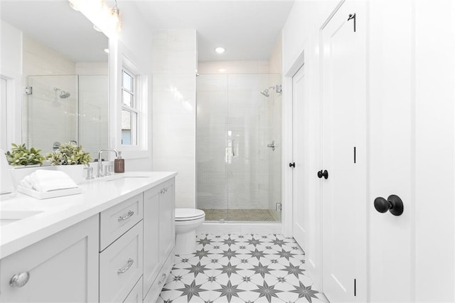 bathroom with a sink, toilet, a shower stall, double vanity, and tile patterned floors