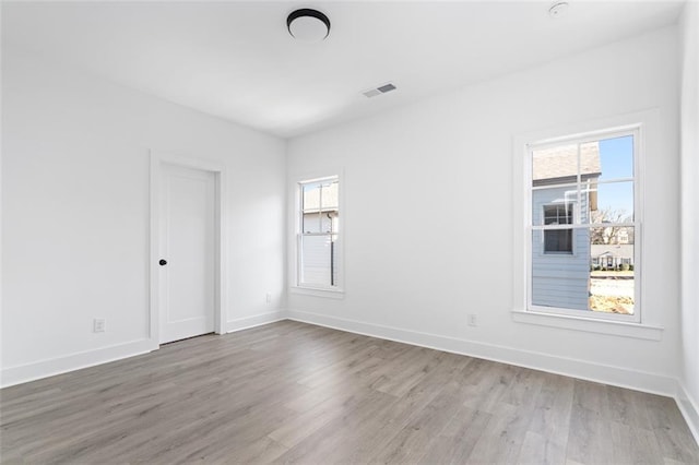 spare room with wood finished floors, baseboards, and visible vents
