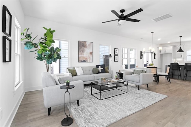 living area with ceiling fan with notable chandelier, light wood-type flooring, visible vents, recessed lighting, and baseboards