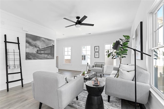 living room featuring visible vents, ceiling fan, light wood finished floors, and baseboards