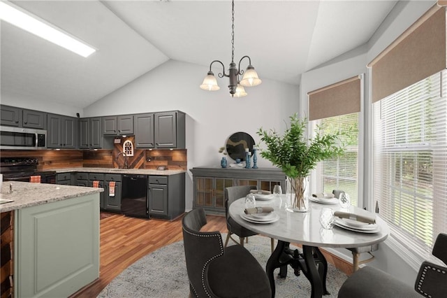 kitchen featuring decorative backsplash, gray cabinetry, black appliances, hanging light fixtures, and lofted ceiling