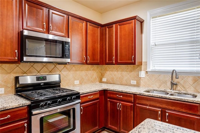 kitchen featuring stainless steel appliances, light stone countertops, sink, and decorative backsplash