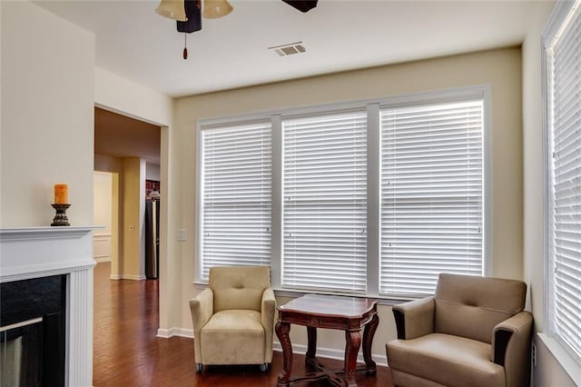 sitting room featuring a fireplace, dark wood-type flooring, and ceiling fan