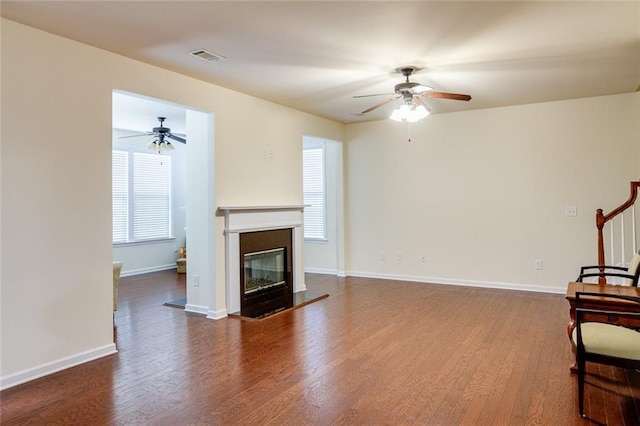 unfurnished living room featuring dark wood-type flooring and ceiling fan