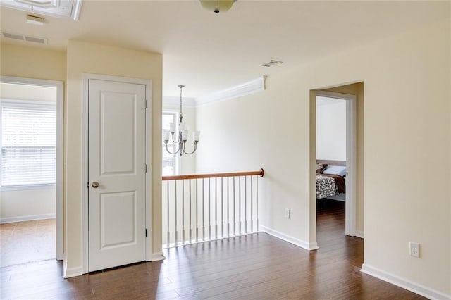 hall with crown molding, dark wood-type flooring, and a chandelier