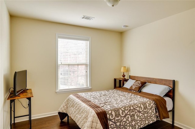 bedroom featuring multiple windows and dark hardwood / wood-style flooring