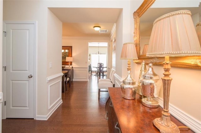 hall with a notable chandelier and dark hardwood / wood-style flooring