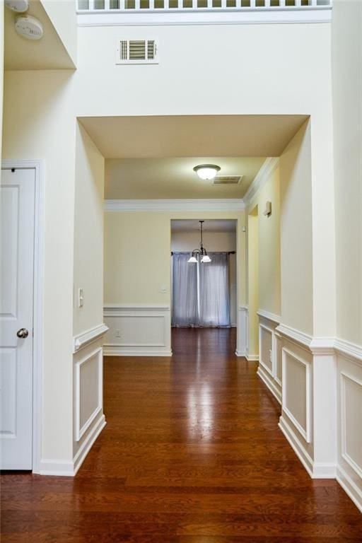 hall with crown molding, a towering ceiling, and dark hardwood / wood-style flooring