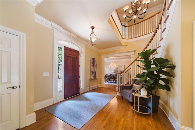 entrance foyer with crown molding, hardwood / wood-style floors, and an inviting chandelier