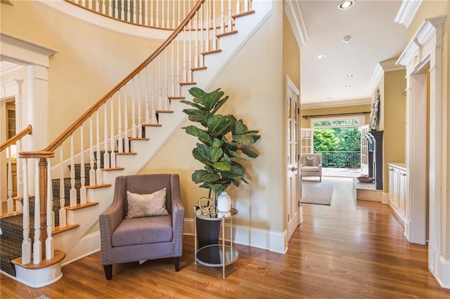 stairway featuring a towering ceiling, ornamental molding, and light hardwood / wood-style floors