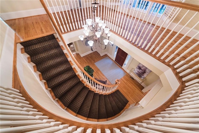 staircase featuring a chandelier, a high ceiling, and wood-type flooring