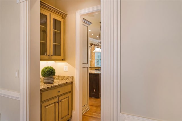 hallway with light wood-type flooring and ornamental molding