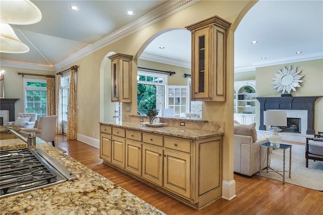 kitchen featuring stainless steel gas cooktop, light stone counters, ornamental molding, and dark hardwood / wood-style floors