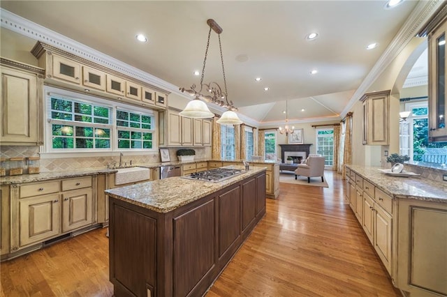 kitchen with light hardwood / wood-style flooring, backsplash, a center island, and a healthy amount of sunlight