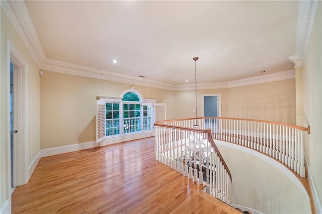 corridor with ornamental molding, light wood-type flooring, and an inviting chandelier