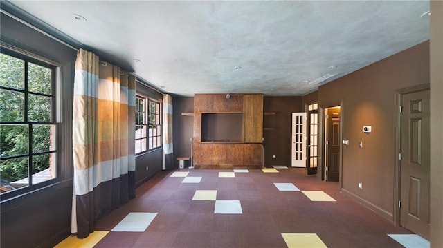 unfurnished room with plenty of natural light and dark colored carpet