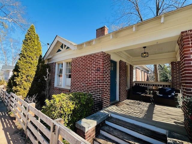 property entrance with a chimney, fence, and brick siding