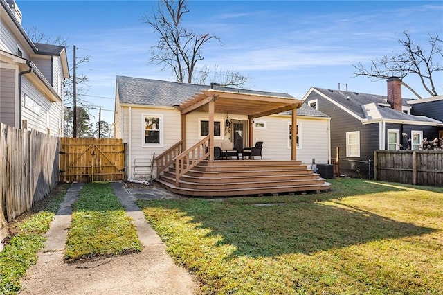 rear view of property featuring a wooden deck, a yard, and central AC