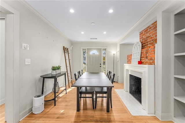 dining space featuring built in shelves, a large fireplace, and light hardwood / wood-style flooring