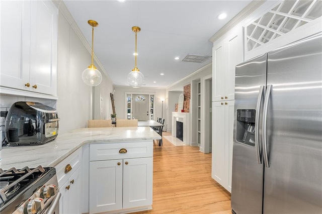 kitchen featuring stainless steel appliances, light stone counters, kitchen peninsula, pendant lighting, and white cabinets