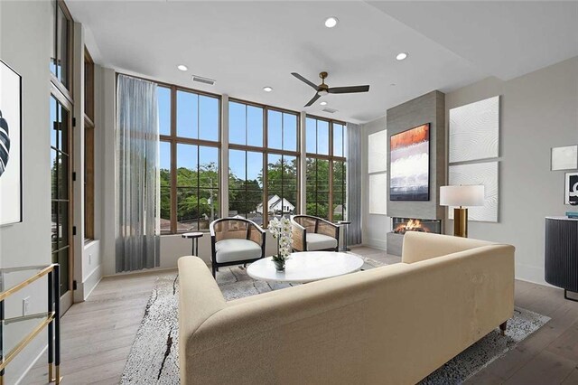 8200 Main St Unit 1206, Woodstock, GA 30188 - living room with a ceiling fan, a large fireplace, recessed lighting, light wood-style flooring, and a wall of windows