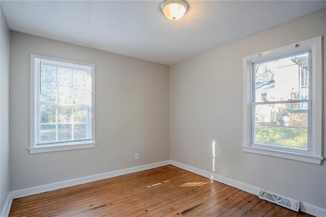 unfurnished room featuring hardwood / wood-style flooring, visible vents, and a wealth of natural light