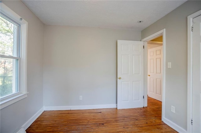 spare room featuring baseboards and wood finished floors