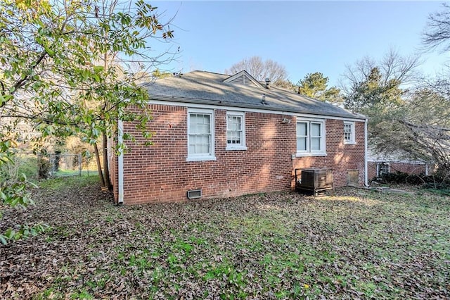 view of side of property featuring crawl space, fence, and brick siding