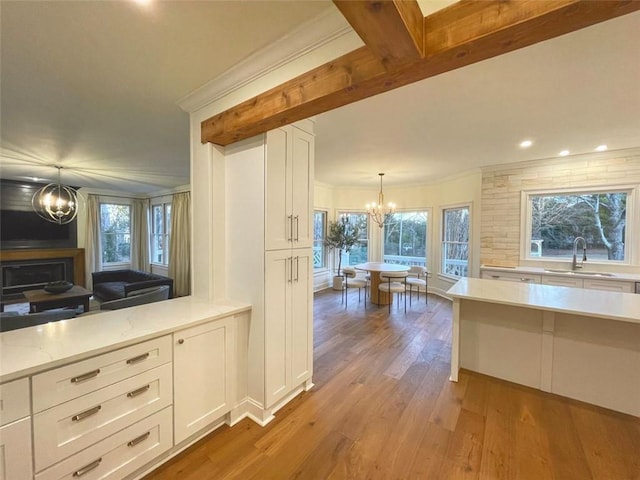 2470 Hopewell Plantation Dr, Milton, GA 30004 - kitchen with a chandelier, white cabinets, wood finished floors, ornamental molding, and pendant lighting