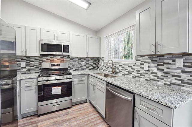 kitchen with decorative backsplash, stainless steel appliances, lofted ceiling, and sink