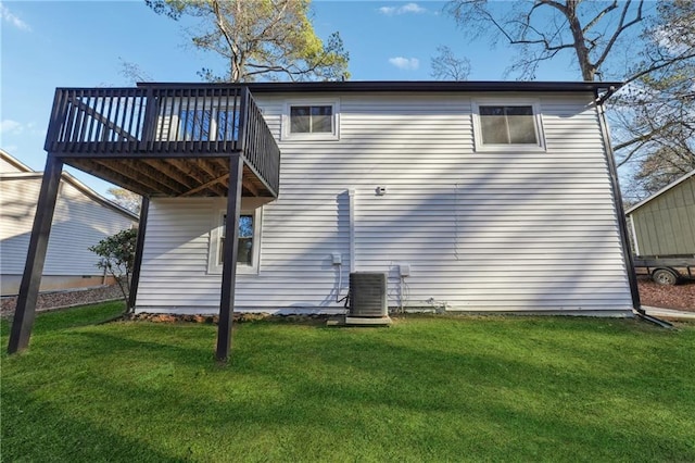 rear view of house with central AC unit, a deck, and a yard