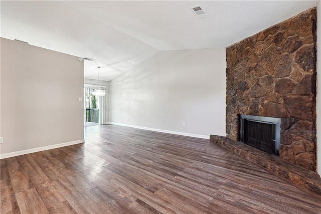 unfurnished living room featuring a stone fireplace, dark hardwood / wood-style floors, and vaulted ceiling